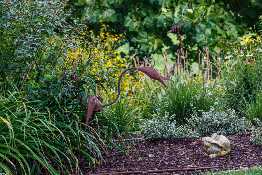 iron sculpture of crane with ceramic rabbit in garden